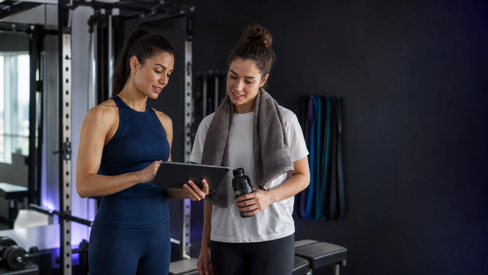 Danışanıyla tablet üzerinden seans ve paket bilgilerini yöneten kadın personal trainer